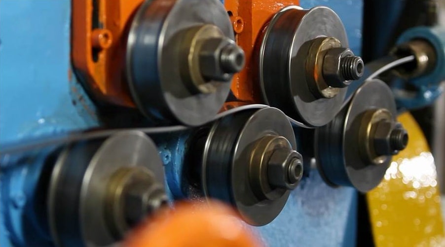 Máquina de precisão usinando componentes de aço inoxidável em um ambiente industrial.